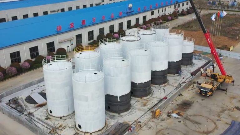 Cluster of large white vertical cylindrical storage tanks under construction at Shijie Heavy Industry facility